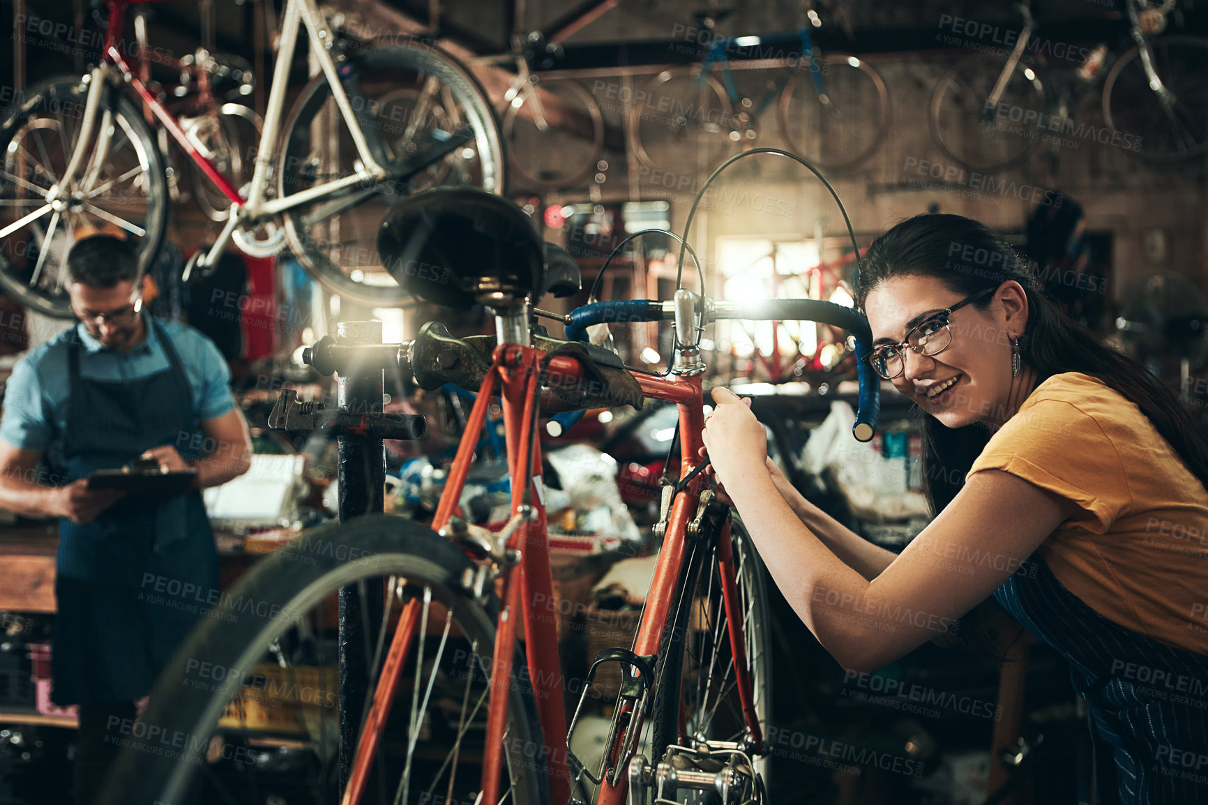 Buy stock photo Happy woman, portrait and bicycle mechanic with inspection, fix or maintenance at repair shop. Young female person, cycling technician or engineer working on bike with tools or equipment at workshop