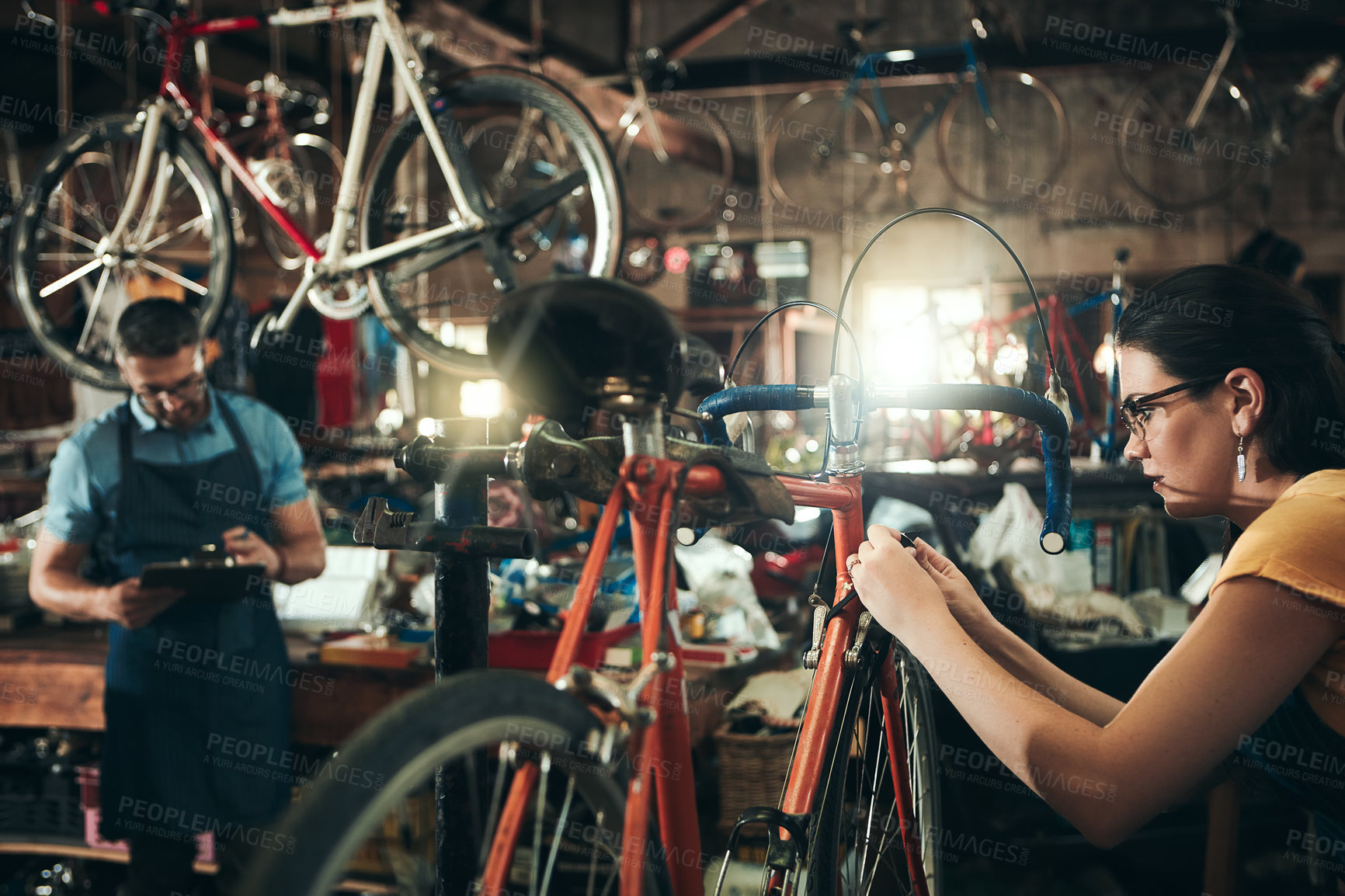 Buy stock photo People, bicycle mechanic and fix with inspection for maintenance or small business at repair shop together. Young man, woman or cycling engineers working on bike with tools or equipment at workshop