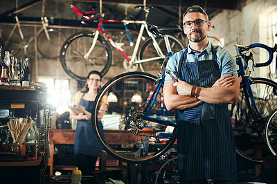 Buy stock photo Portrait of a mature man working in a bicycle repair shop with his coworker in the background