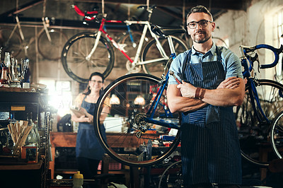 Buy stock photo Man, portrait and arms crossed at bicycle repair shop for work in maintenance garage. Bike, mechanic and service with woman handyman coworker for startup, small business and workshop for fixing