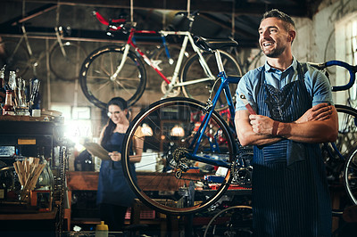 Buy stock photo Shot of a mature man working in a bicycle repair shop with his coworker in the background