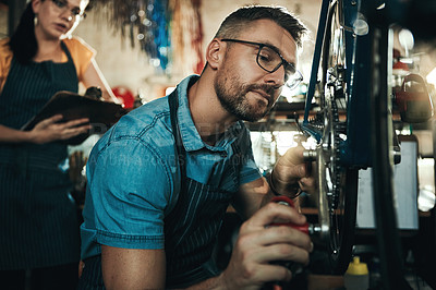 Buy stock photo Shot of a man and woman working together in a bicycle repair shop