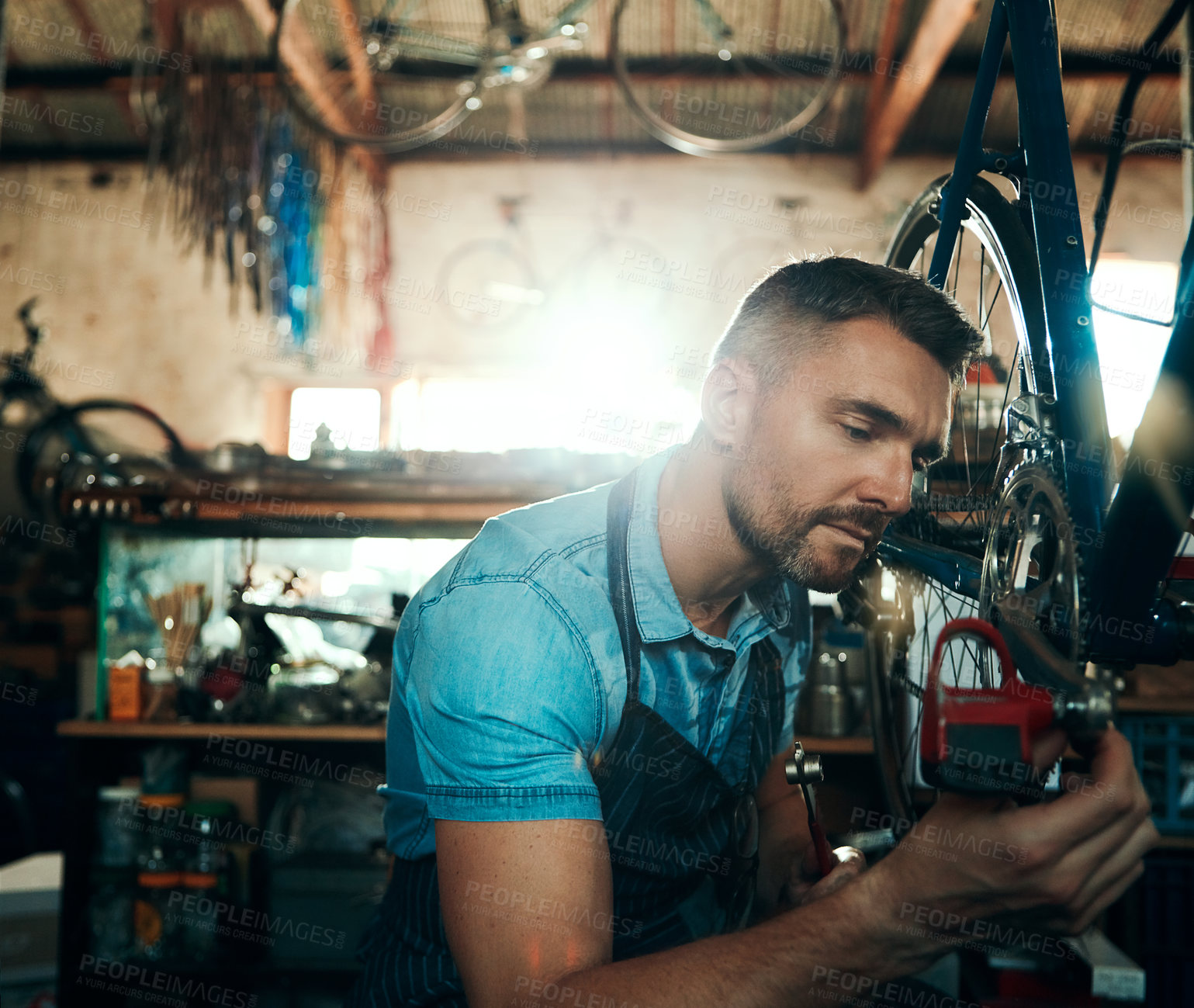 Buy stock photo Bicycle technician, repair and working in shop with tyre, chain and tools for maintenance or cycling. Man, mechanic and bike in workshop as handyman for gear, inspection and safety with service