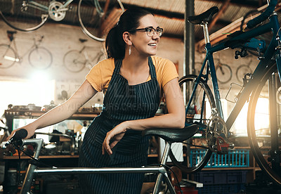 Buy stock photo Shot of a young woman working in a bicycle repair shop
