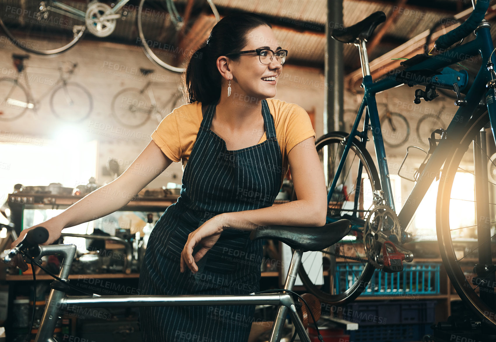 Buy stock photo Workshop, woman and bicycle repair shop with mechanic, technician or maintenance with apron. Happy, service smile and business owner with startup, pride or bike for fixing with entrepreneur in garage