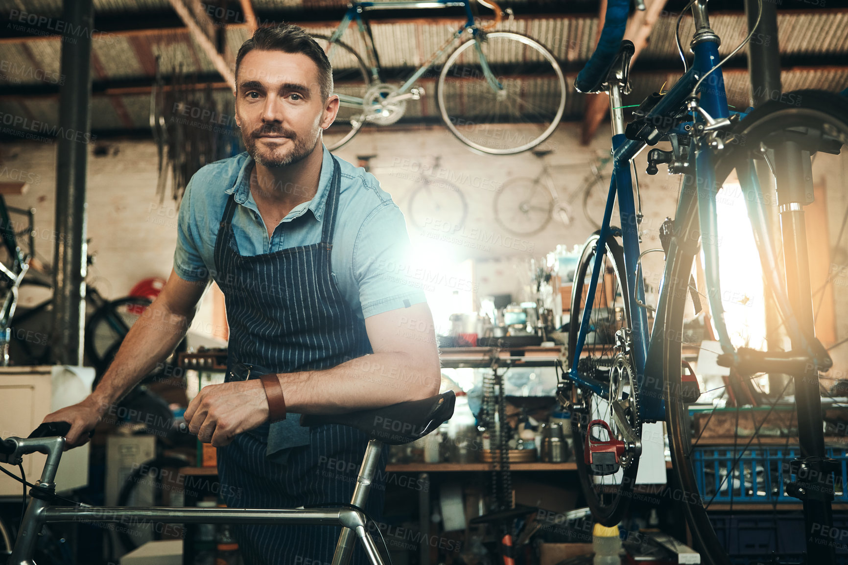 Buy stock photo Man, bicycle shop and portrait for maintenance job, startup with transport service. Bike, mechanic and male entrepreneur in workshop with serious face, professional or sustainable business with apron