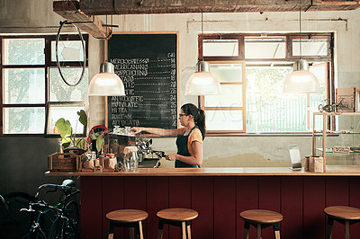 Buy stock photo Shot of a young barista working in her coffee shop