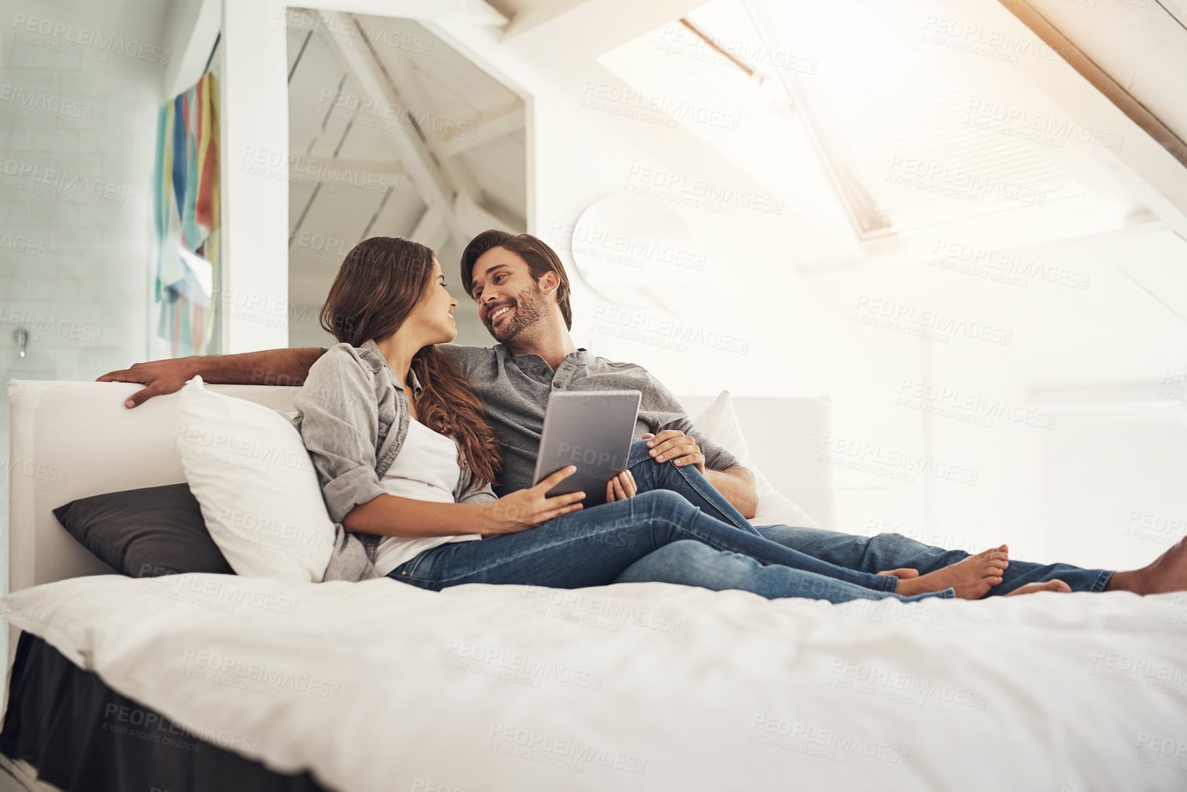 Buy stock photo Happy, home and couple in bedroom on tablet for bonding, loving relationship and relax together. Marriage, love and man and woman on digital tech for online videos, streaming and watching movies