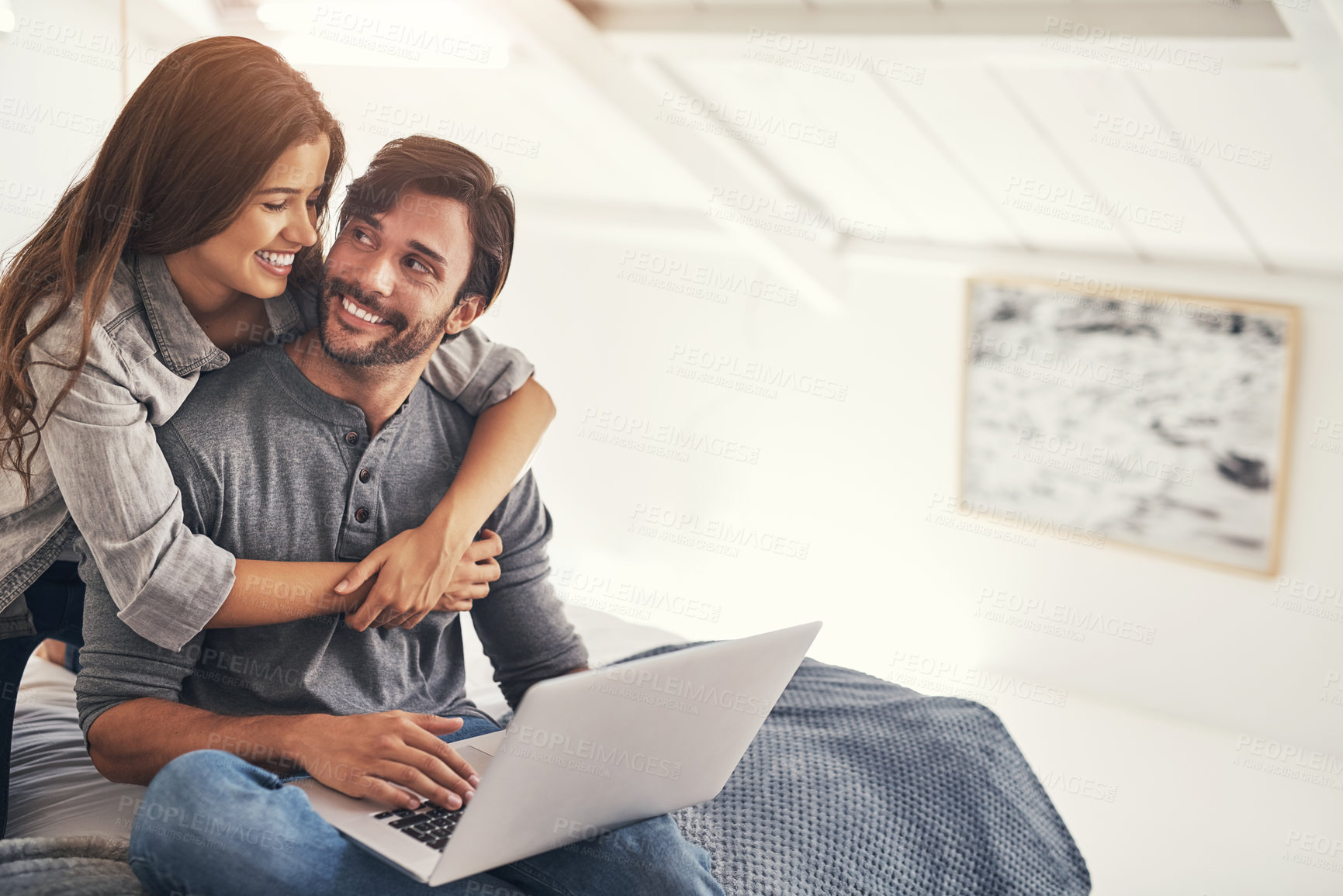 Buy stock photo Couple, laptop and smile or hug in bedroom with online search for holiday destination or discount offers on travel. People, relax or embrace on bed in home with mockup, social media browsing and love