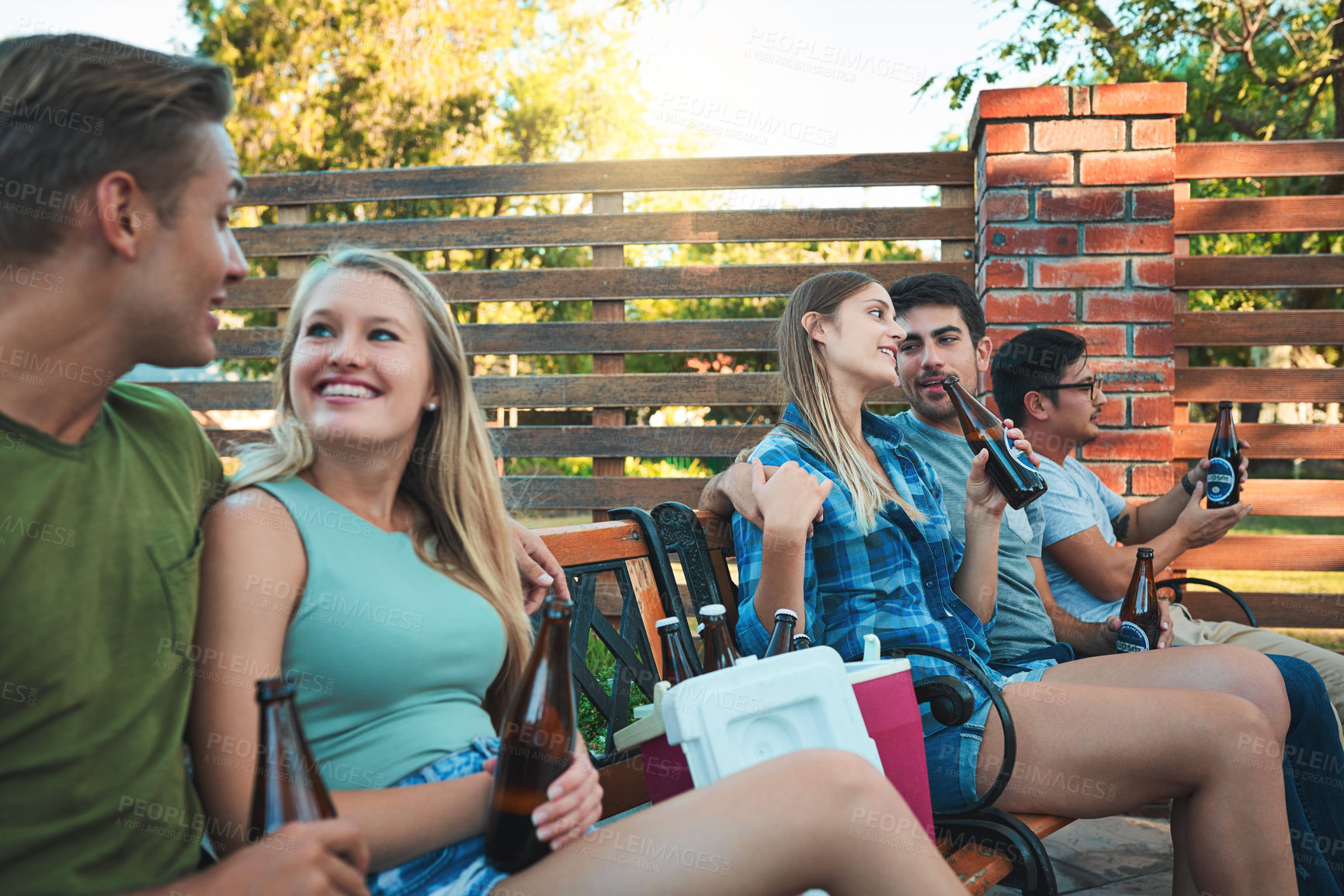 Buy stock photo Couple of happy friends, drink and beer at outdoor party, celebration or Octoberfest in summer. People, alcohol bottle and together at park with group for holiday, relax or talk at social gathering