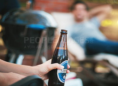 Buy stock photo Cropped shot of a woman holding a bottle of beer at a get together