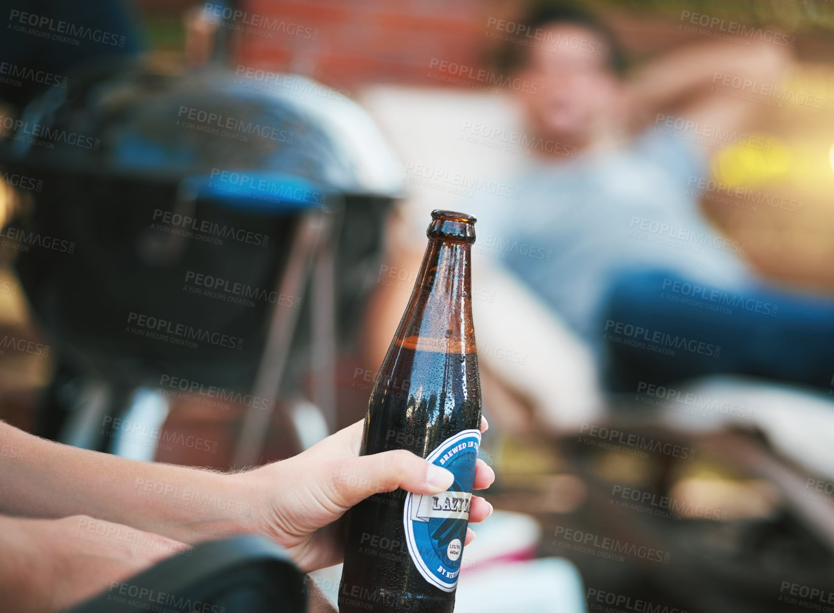Buy stock photo Cropped shot of a woman holding a bottle of beer at a get together