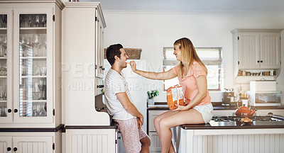 Buy stock photo Shot of a young woman feeding her boyfriend a snack in the kitchen