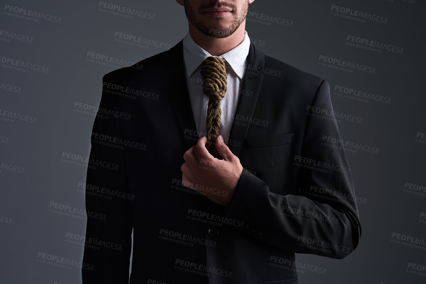 Buy stock photo Cropped studio shot of a businessman with a noose tied around his neck for a tie against a gray background