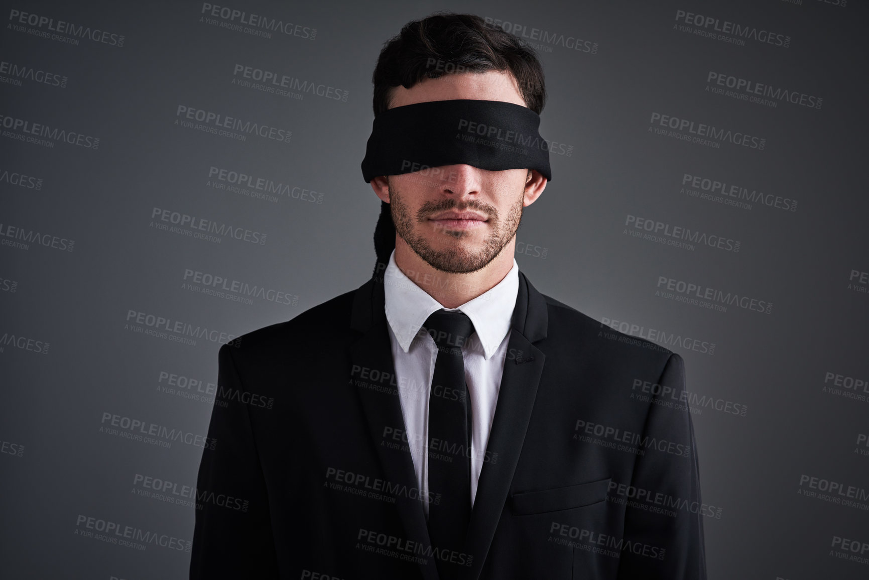 Buy stock photo Studio shot of a young businessman wearing a blindfold against a gray background