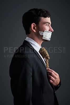 Buy stock photo Studio shot of a businessman with rope around his neck and money taped over his mouth against a gray background