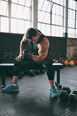 Buy stock photo Shot of a young man working out with dumbbells at the gym