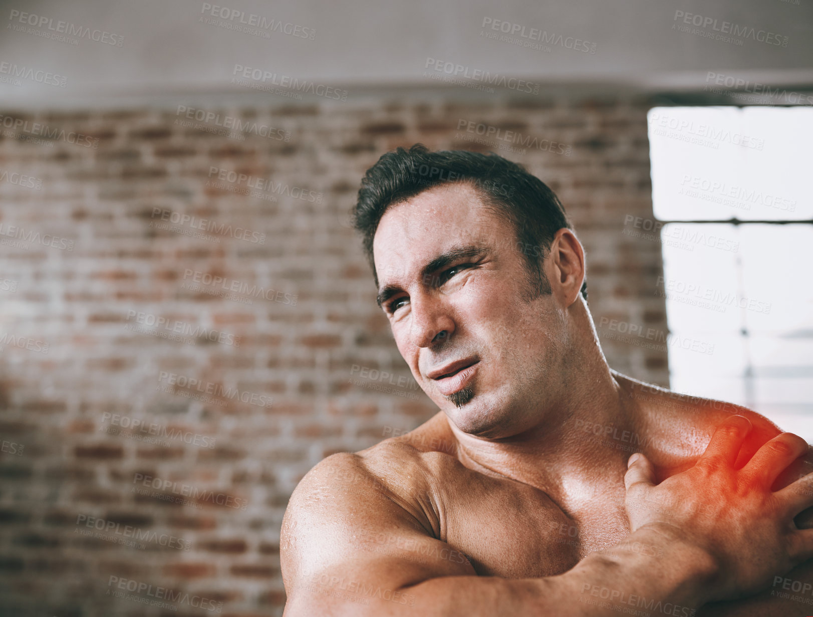 Buy stock photo Shot of a man suffering from a shoulder injury at the gym