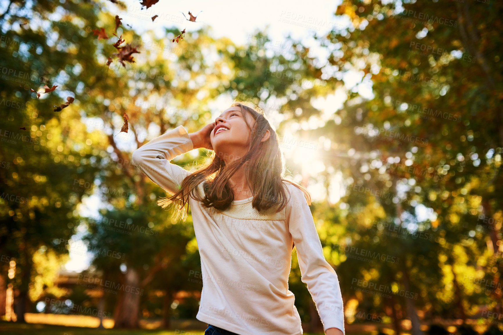 Buy stock photo Shot of a happy little girl playing in the autumn leaves outdoors