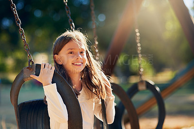 Buy stock photo Shot of a happy little girl having fun on the swings in the playground