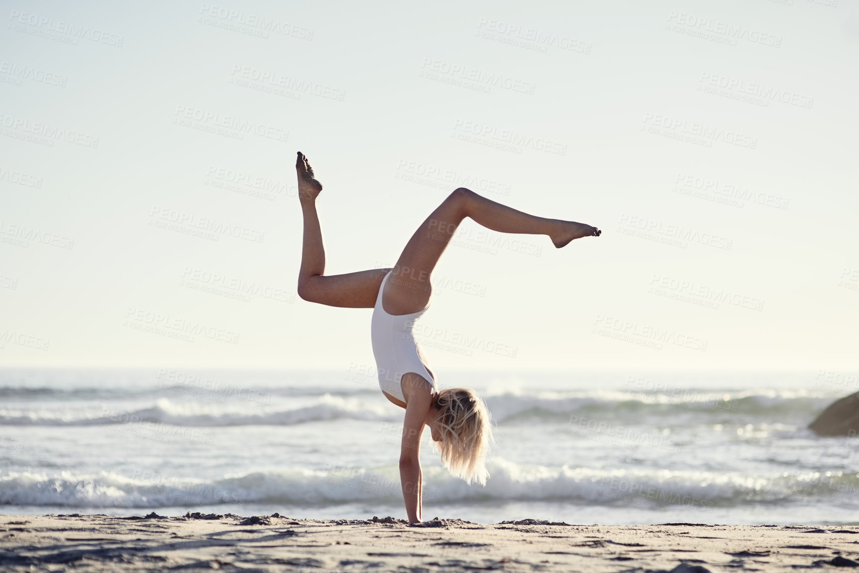 Buy stock photo Full length shot of a young woman doing a handstand on the beach