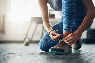 Buy stock photo Shot of a woman tying her shoelaces in a gym