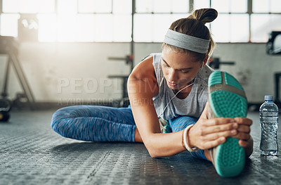 Buy stock photo Shot of a young attractive woman stretching in a gym