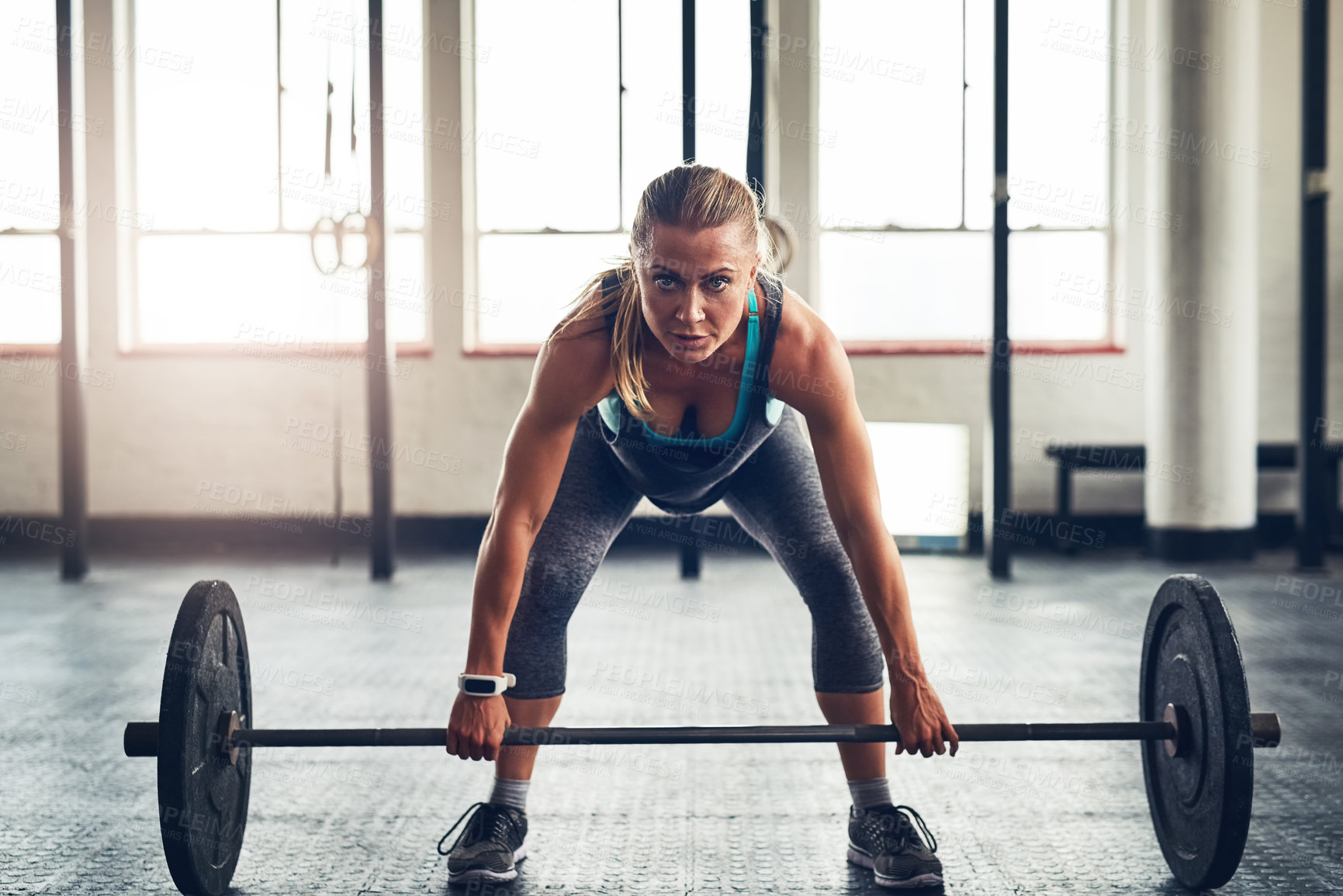 Buy stock photo Shot of a sporty young woman lifting weights at the gym