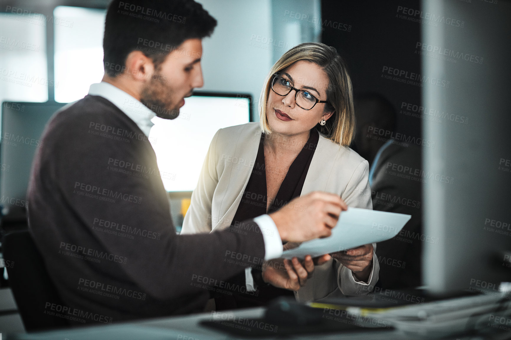 Buy stock photo Shot of two businesspeople discussing a document while sitting at a desk