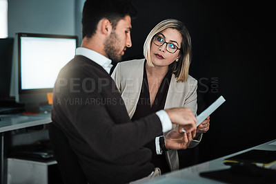 Buy stock photo Shot of two businesspeople discussing a document while sitting at a desk