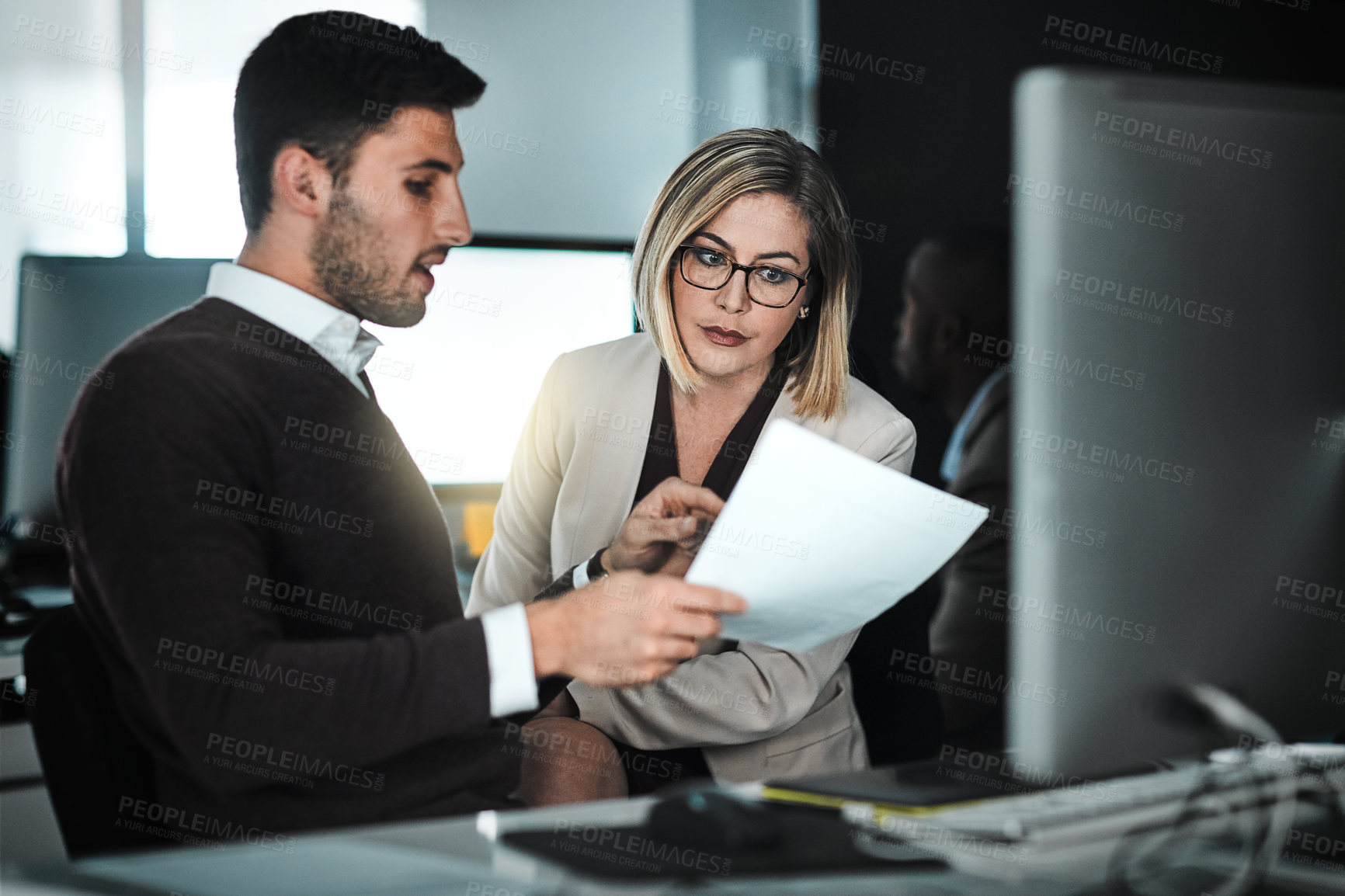 Buy stock photo Shot of two businesspeople discussing a document while sitting at a desk