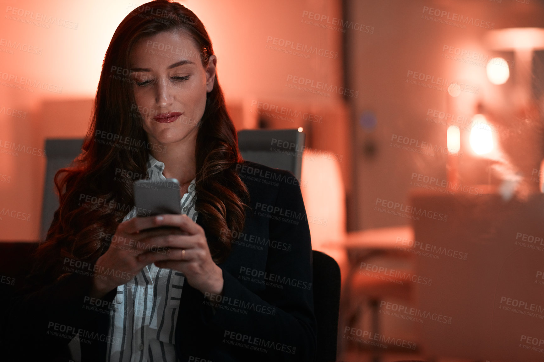 Buy stock photo Shot of a businesswoman using a mobile phone during a late night at work