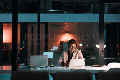 Buy stock photo Shot of a businesswoman using a laptop at her desk during a late night at work