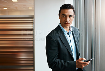 Buy stock photo Shot of a well-dressed businessman using his cellphone at the office