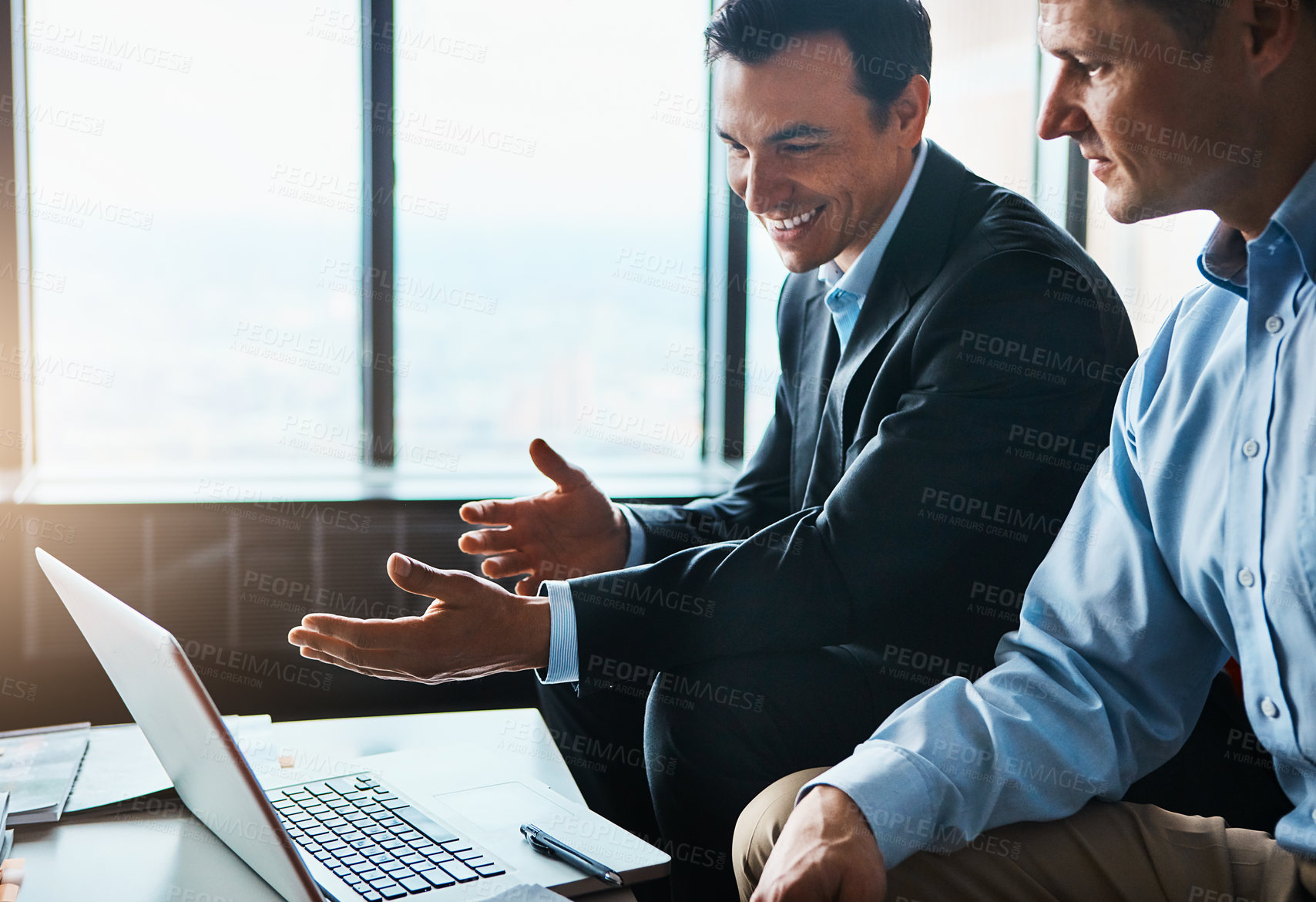 Buy stock photo Shot of two businessmen having a discussion while sitting by a laptop