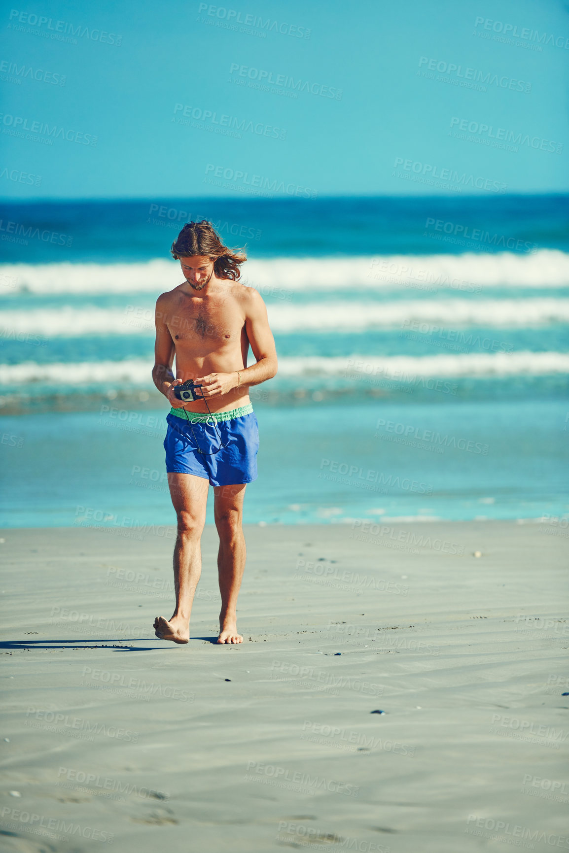 Buy stock photo Shot of a young man spending the day at the beach