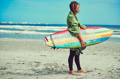 Buy stock photo Shot of a young surfer strolling on the beach with his surfboard