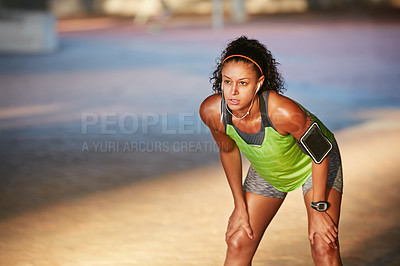 Buy stock photo Shot of a sporty young woman taking a break while out for a run