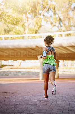 Buy stock photo Rear view shot of a sporty young woman out for a run