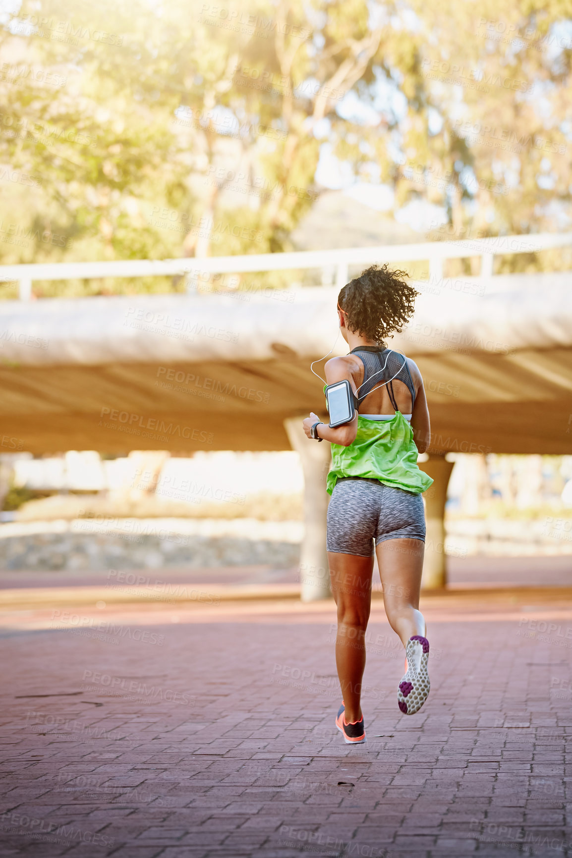 Buy stock photo Rear view shot of a sporty young woman out for a run