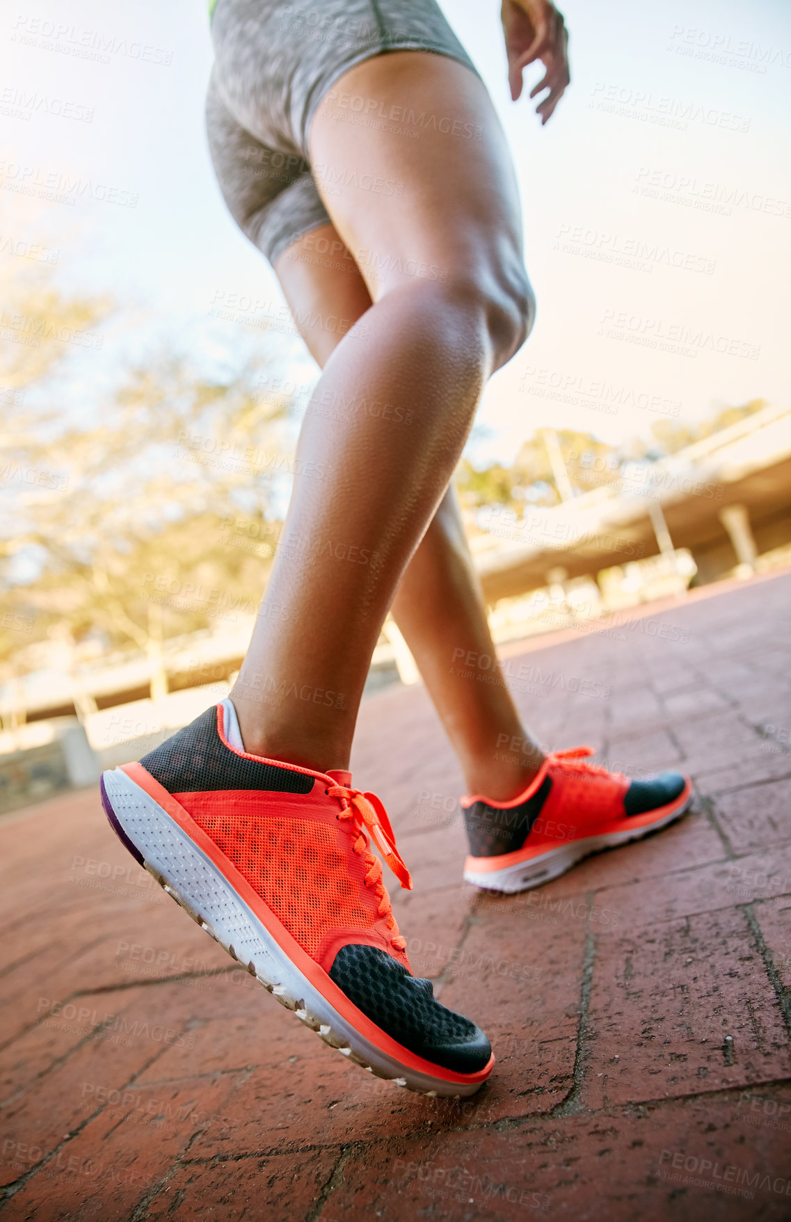 Buy stock photo Low angle shot of an unrecognizable athletic woman out for a run in the city