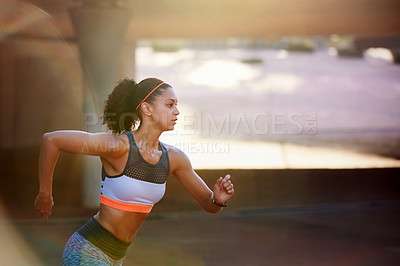 Buy stock photo Cropped shot of an attractive young woman taking a run through the city