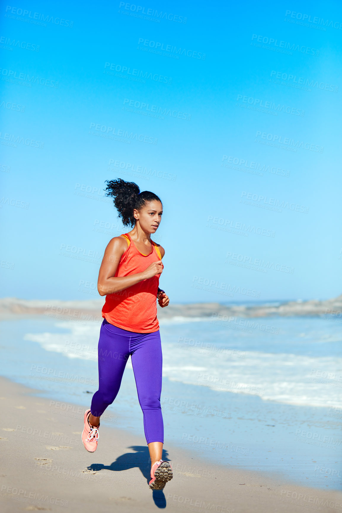 Buy stock photo Shot of a sporty young woman out at the beach for her morning run