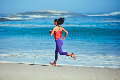 Buy stock photo Shot of a sporty young woman out at the beach for her morning run