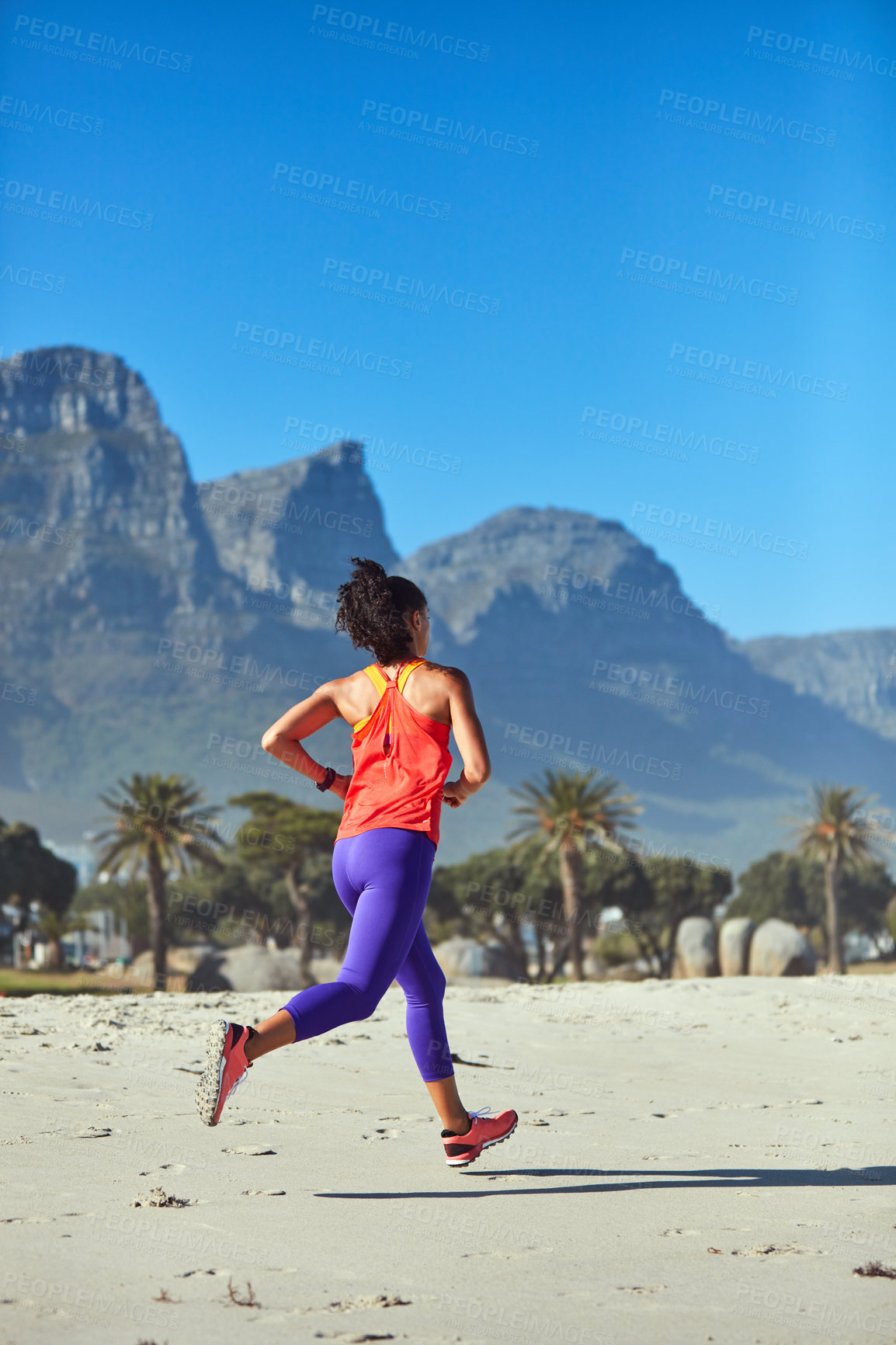 Buy stock photo Shot of a sporty young woman out at the beach for her morning run