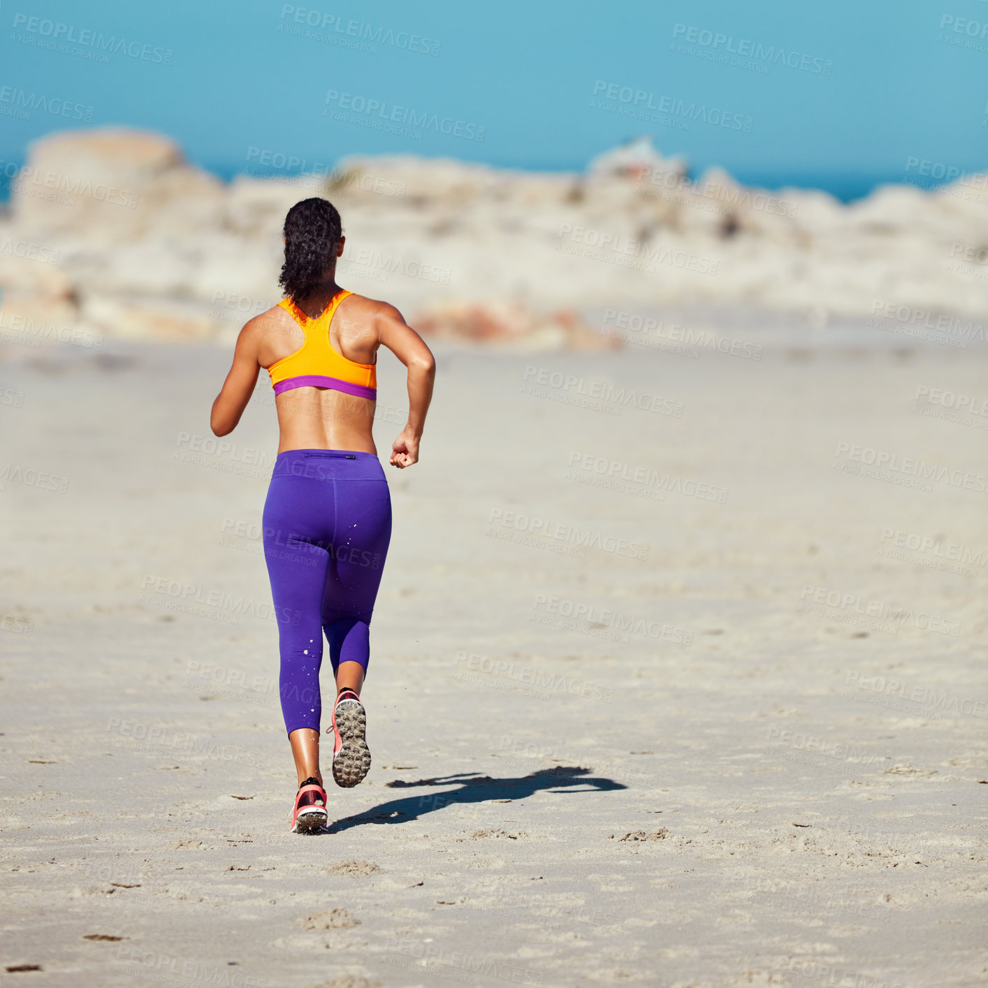 Buy stock photo Shot of a sporty young woman out at the beach for her morning run