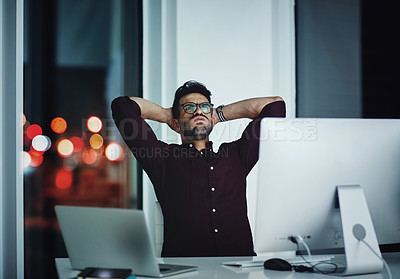 Buy stock photo Shot of a young businessman feeling frustrated while working at his desk during a late night at work