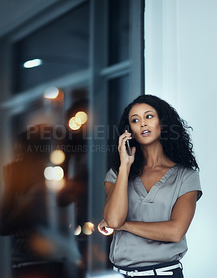 Buy stock photo Shot of a young businesswoman talking on a mobile phone during a late night at work