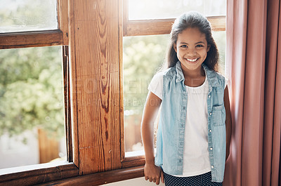 Buy stock photo Portrait of a happy young girl standing next to a window at home