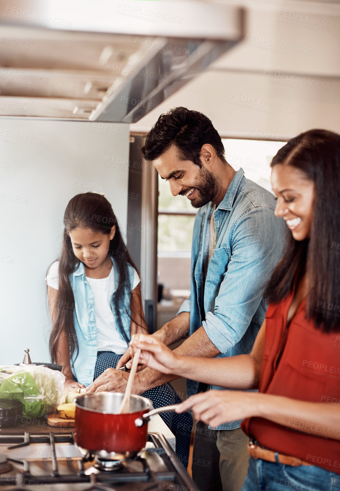 Buy stock photo Shot of a happy young family preparing a meal in the kitchen together at home